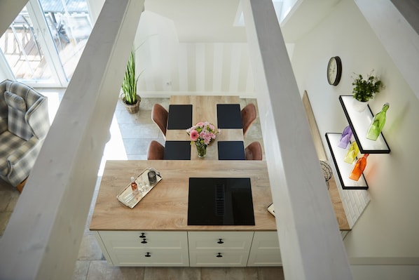 A modern kitchen with a wooden countertop, black appliances, and a dining area with a table and chairs. - Haus Daglind Apartment 3 mit Saunafass und Balkon (Büsum)