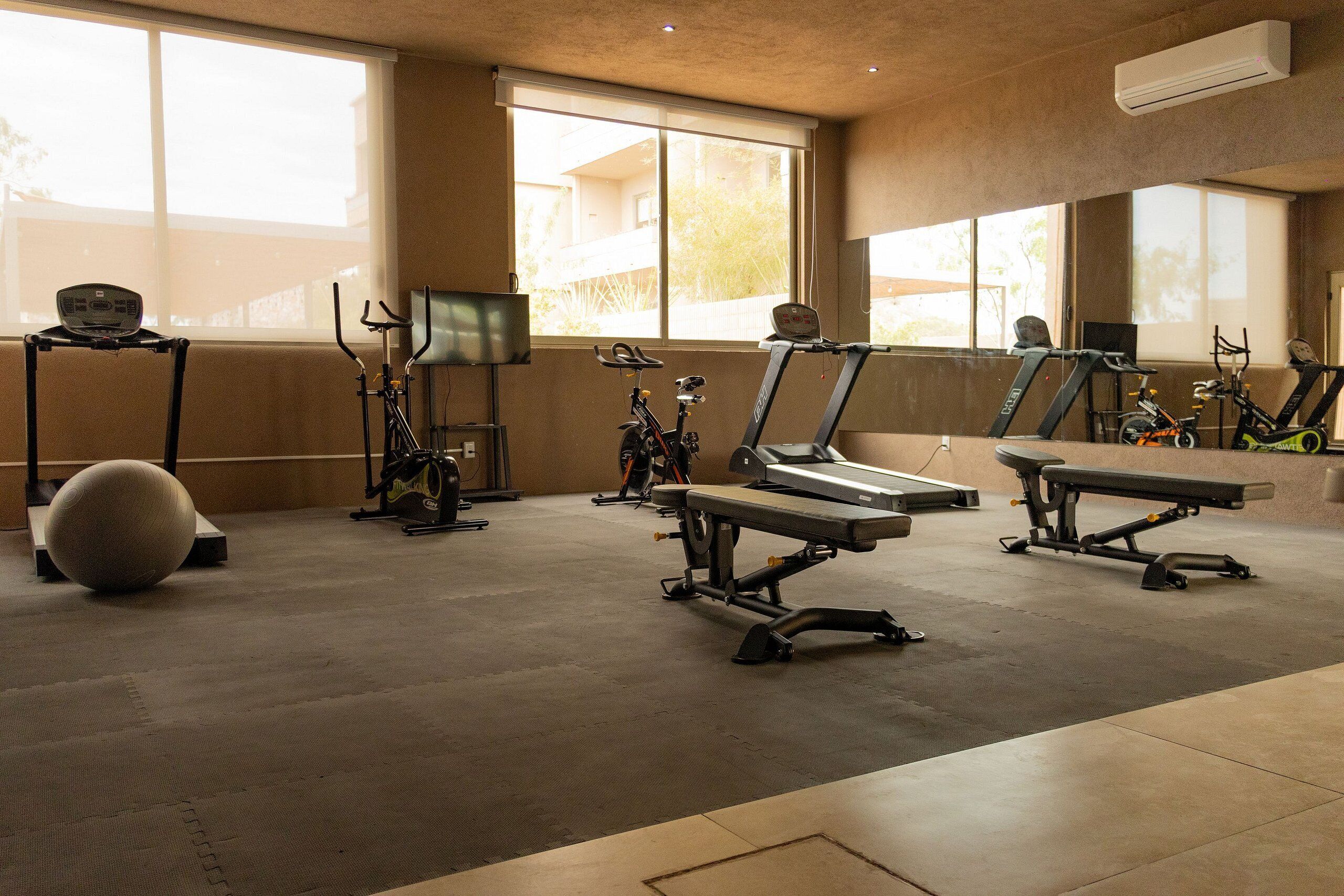 A gym with exercise equipment including treadmills, stationary bikes, and a rowing machine.