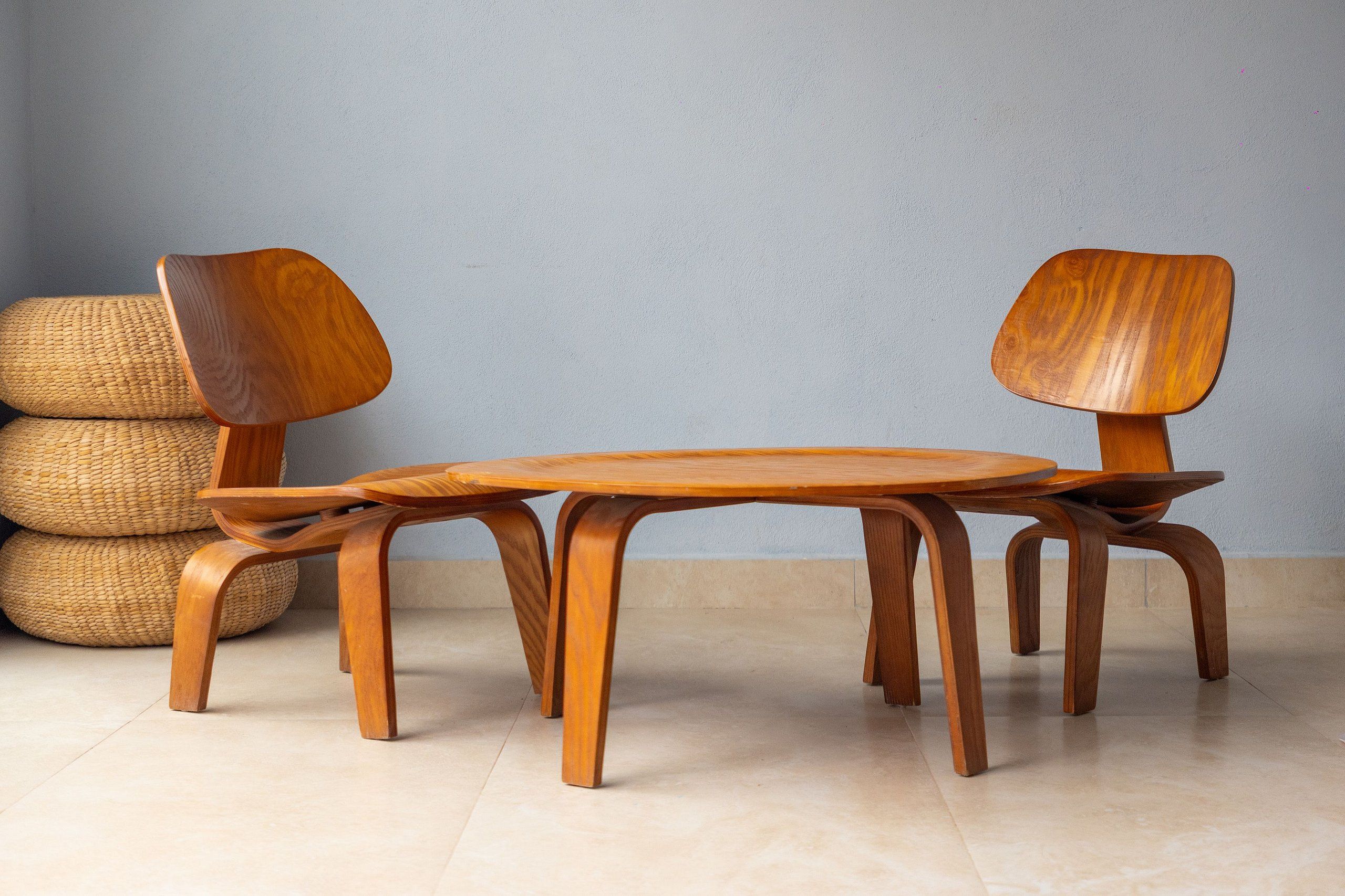 Une table de salle à manger en bois, accompagnée de quatre chaises, d’un panier tressé et d’un mur à la texture particulière.