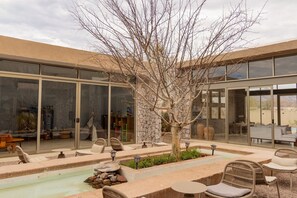 Un patio moderno al aire libre con un árbol, asientos y una fuente de agua.