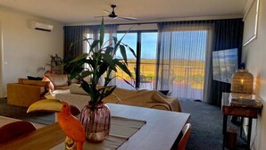 A hotel room with a dining area, a large window with a view, a ceiling fan, and a plant on the table. - Wamoon Retreat ~ Luxe House - Gateway to Wilsons Prom  (Yanakie)