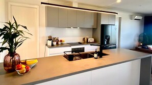 A modern kitchen with a central island, built-in appliances, and a minimalist design. - Wamoon Retreat ~ Luxe House - Gateway to Wilsons Prom  (Yanakie)