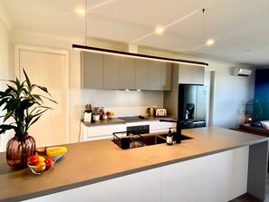 A modern kitchen with a central island, built-in appliances, and a minimalist design. - Wamoon Retreat ~ Luxe House - Gateway to Wilsons Prom  (Yanakie)