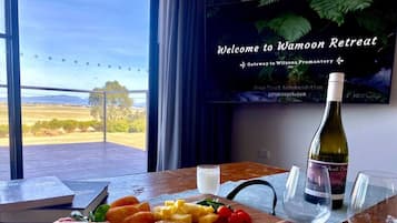 A welcome sign for Wamoon Retreat, a glass of wine, and a board with cheese, crackers, and ham.