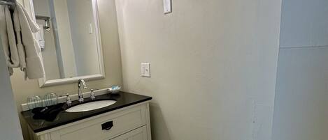 A bathroom with a white sink, mirror, and toilet.