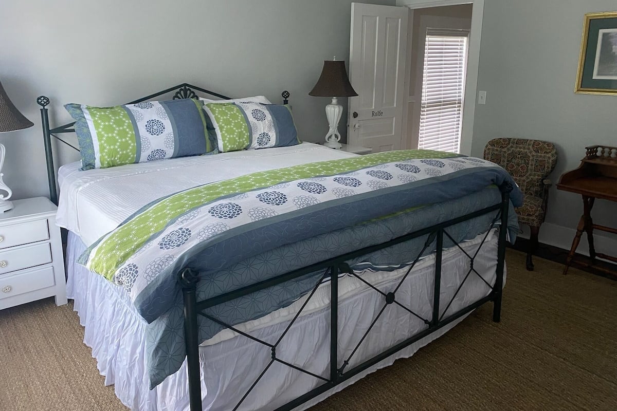 A bedroom with a bed, bedside tables, a chair, and a door.