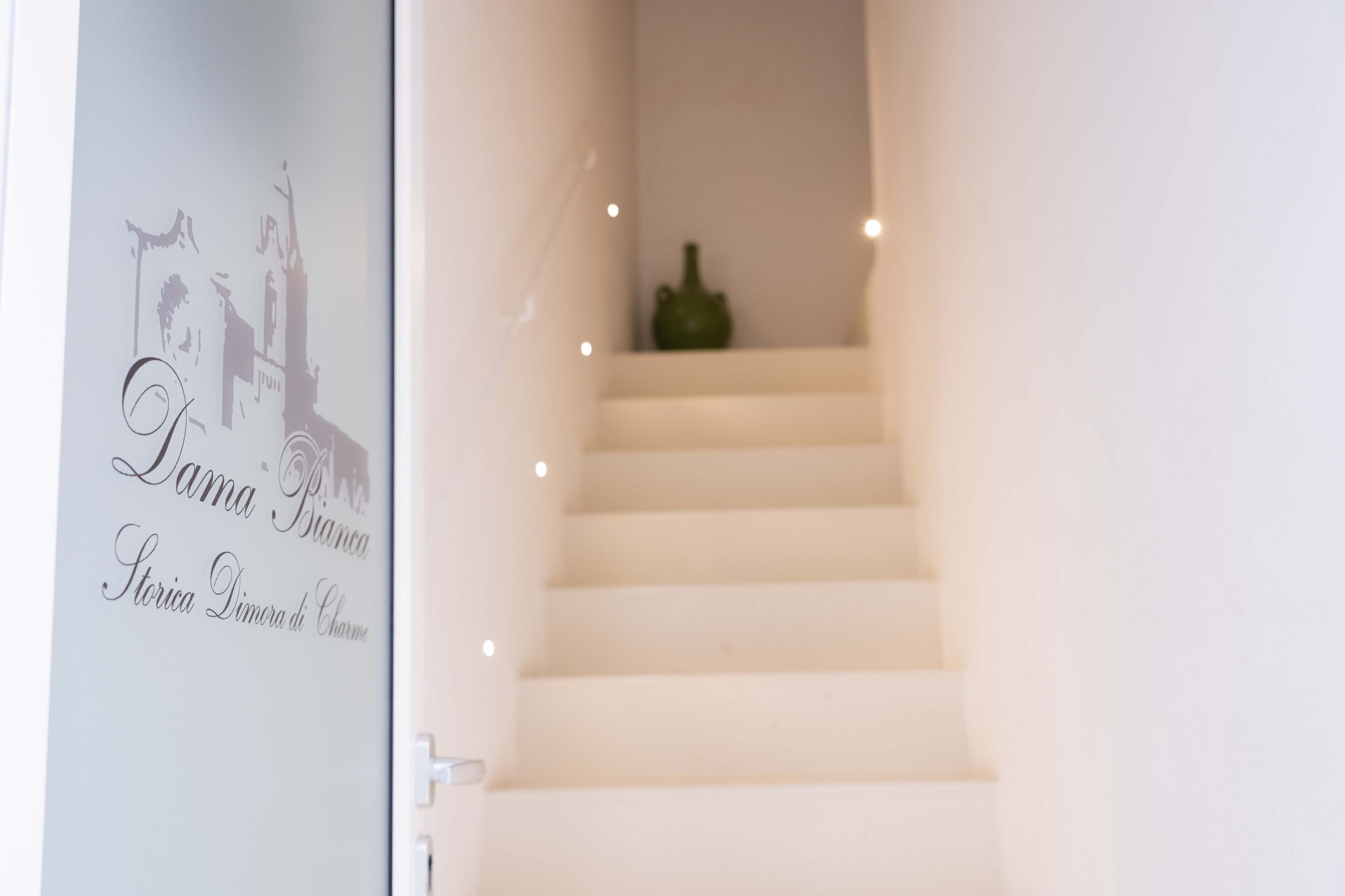 Una escalera con un letrero en la pared que dice "Dama Bianca Storia Dimora di Chime".