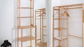 Un armario de madera con varios estantes y espacio para colgar, situado junto a un espejo.