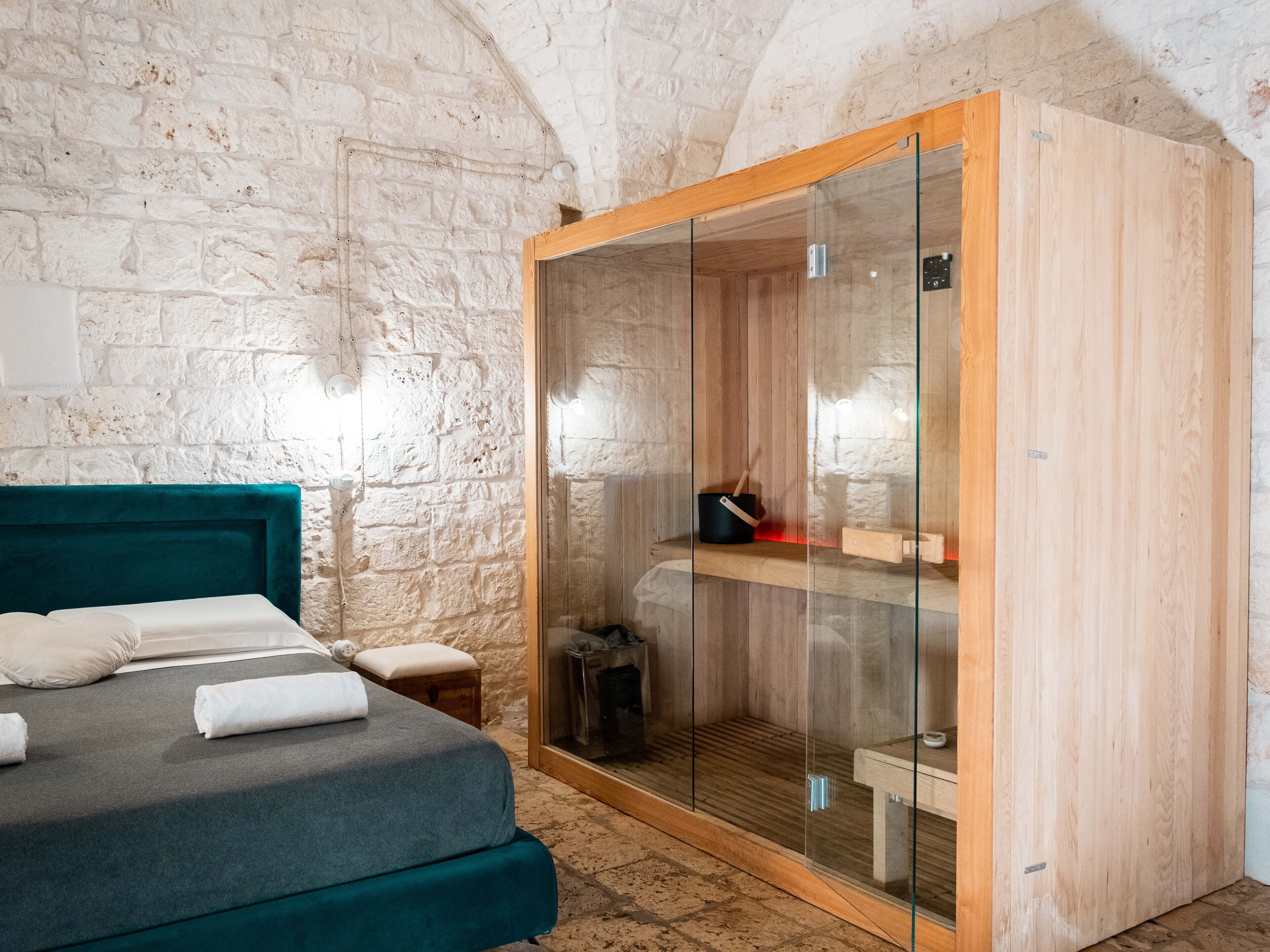 A bedroom with a bed, a wooden wardrobe, and a stone wall.