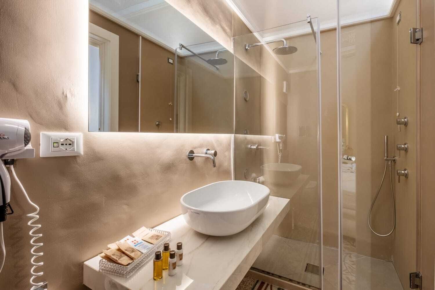 A modern bathroom with a large vessel sink, a handheld showerhead, and a glass-enclosed shower.
