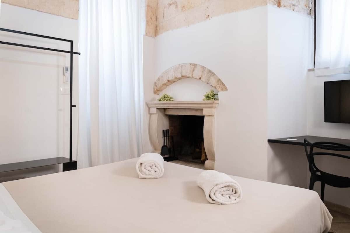 Una habitació d'hotel amb un llit, una llar de foc, un escriptori i una televisió.