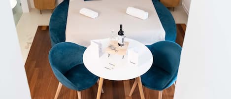 Una habitació d'hotel moderna amb un llit gran, dues taules de nit, una taula rodona amb cadires i una obra d'art penjada a la paret.