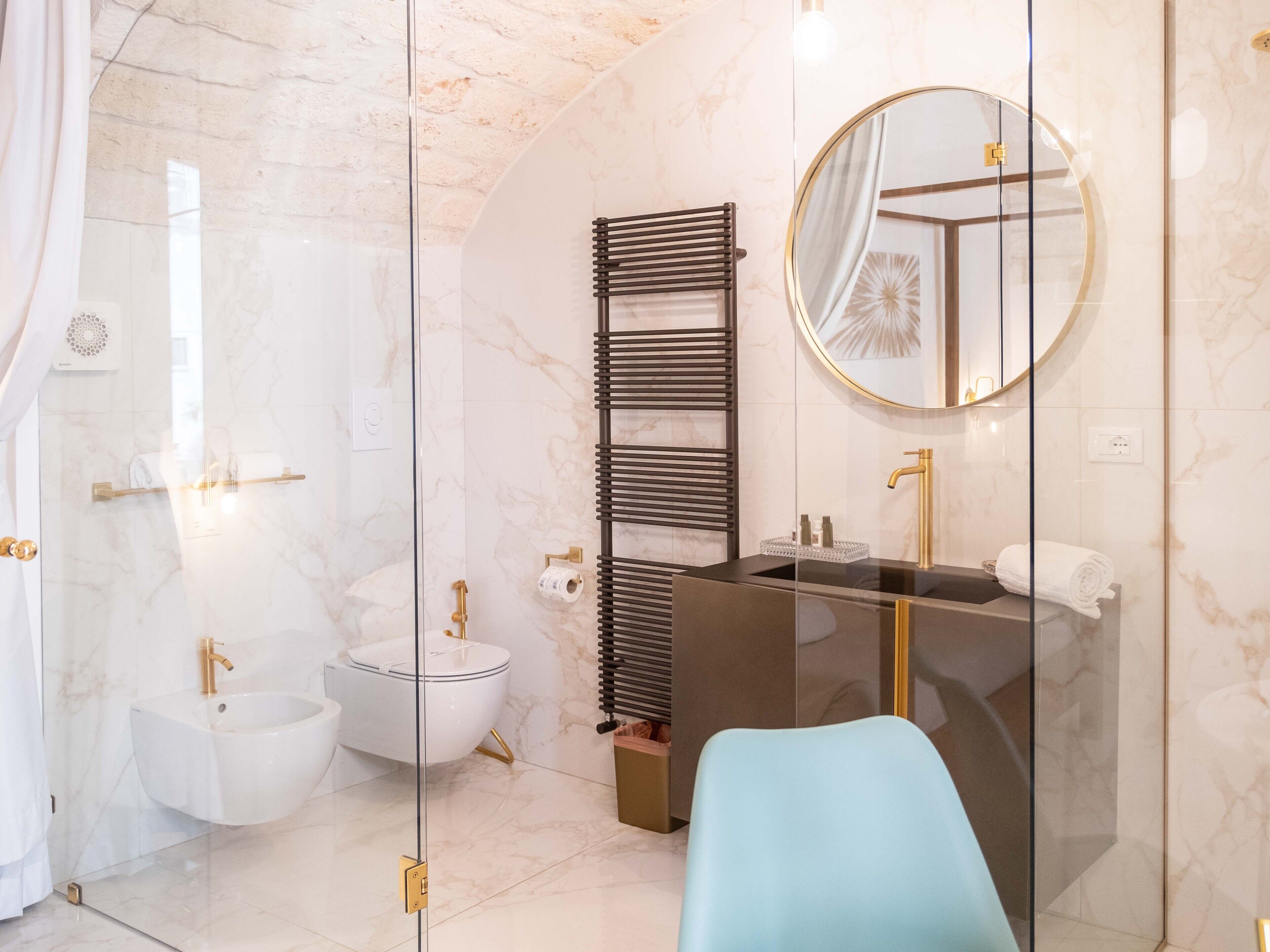 Une salle de bain moderne dotée d’une douche à parois de verre, d’un bidet, d’un meuble-lavabo avec un miroir et un porte-serviettes.