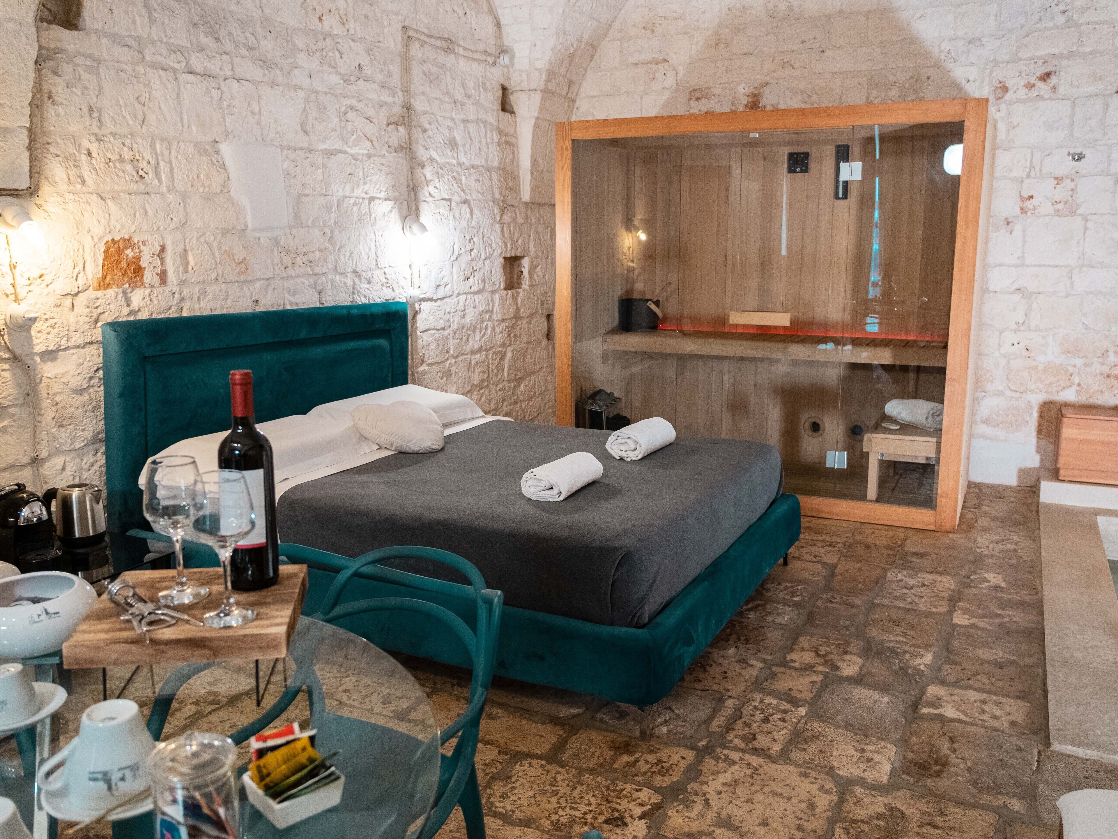 Une pièce confortable avec un lit, une table sur laquelle se trouve une bouteille de vin et un miroir.