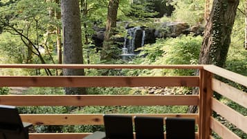 Eine Holzterrasse mit Blick auf einen Wasserfall, umgeben von Bäumen.
