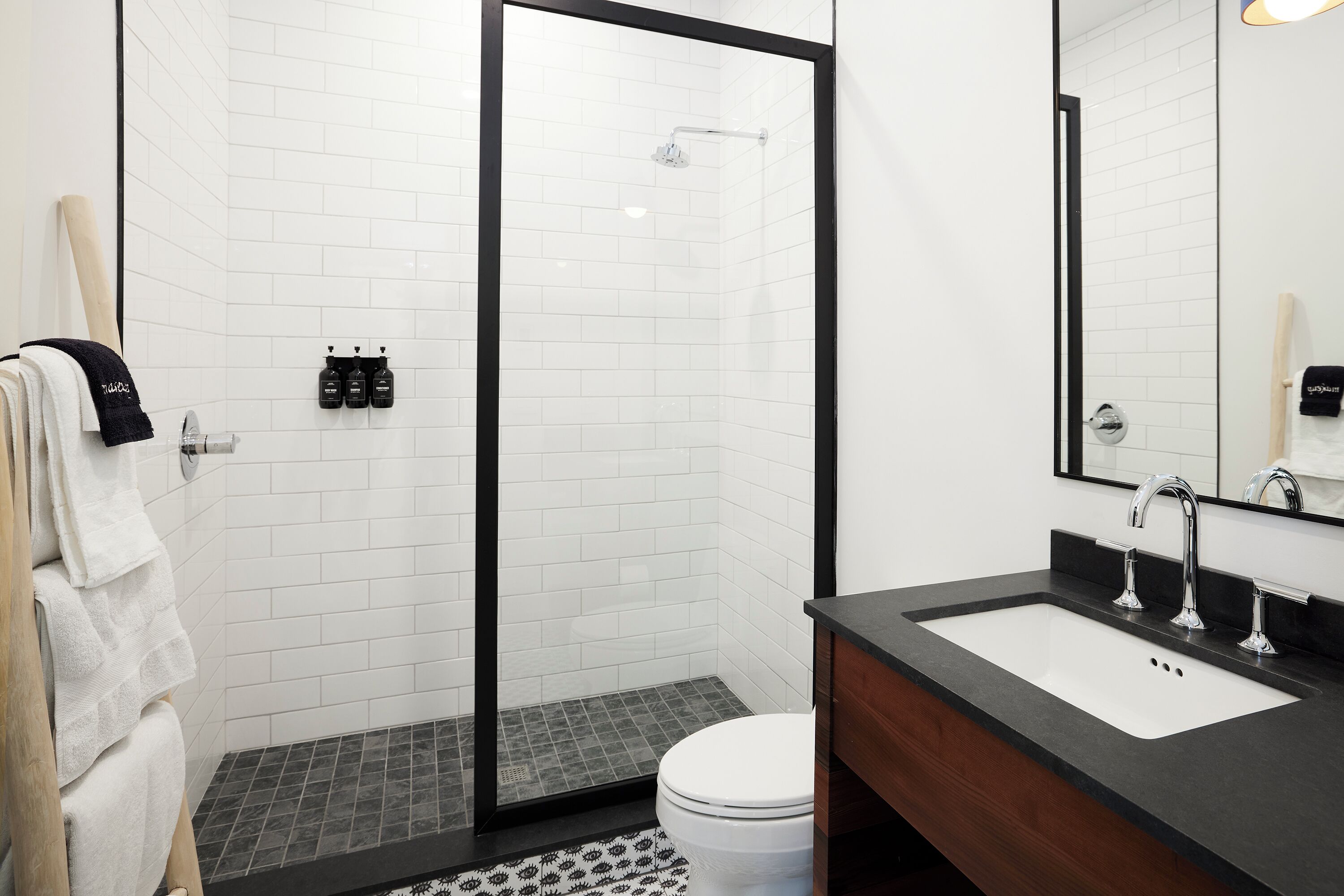 A modern bathroom with a glass-enclosed shower, a white toilet, and a black countertop sink.