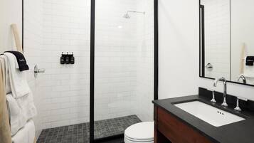 A modern bathroom with a glass-enclosed shower, a white toilet, and a black countertop sink.