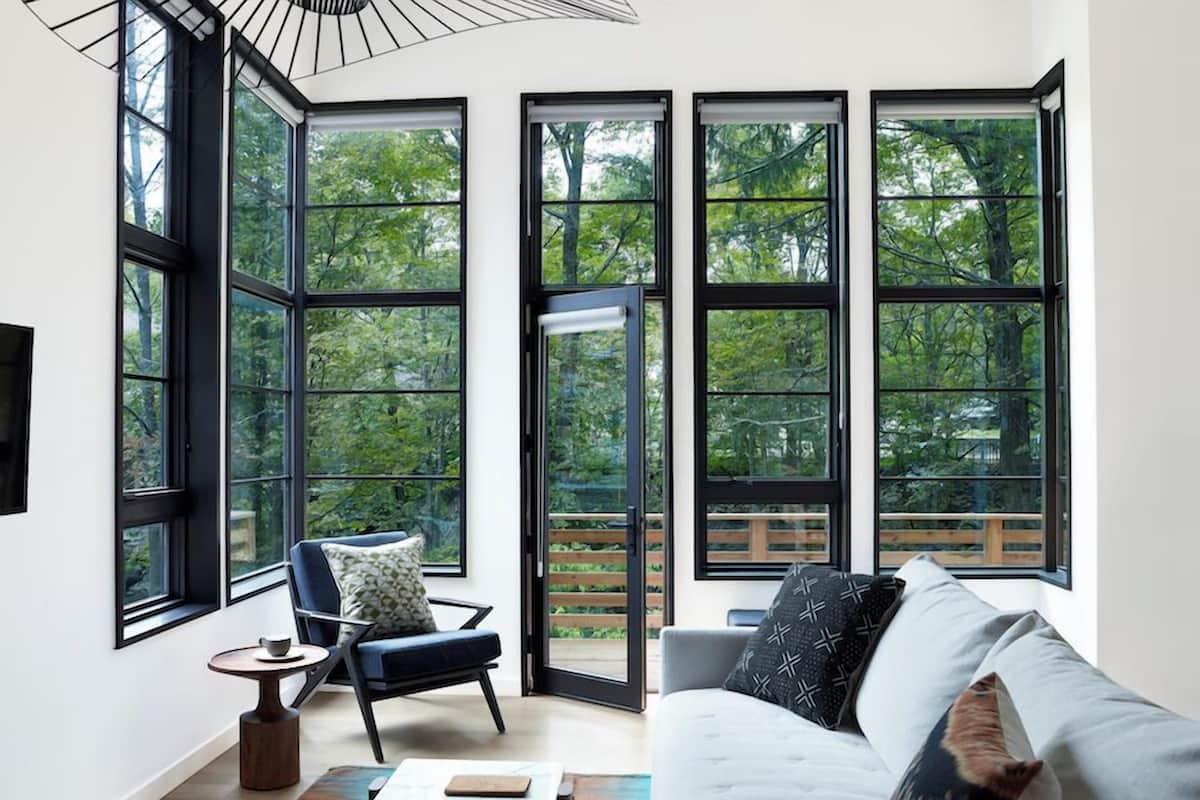 A modern living room with large windows, a sofa, a chair, and a small table.