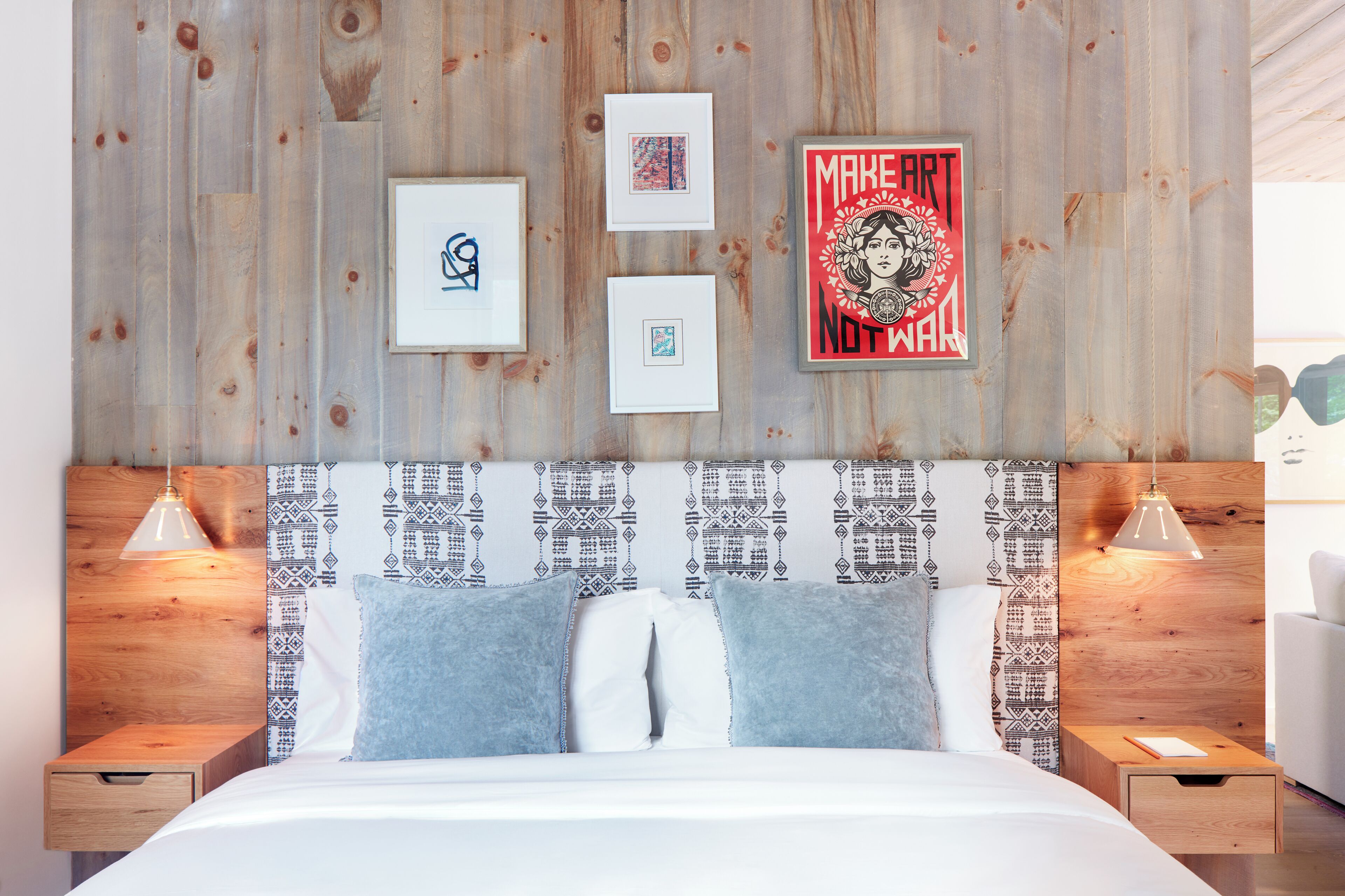 A bedroom with a wooden headboard, a bed with blue and white bedding, and framed artwork on the wall.