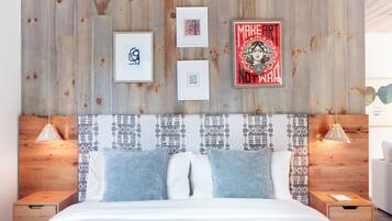 A bedroom with a wooden headboard, a bed with blue and white bedding, and framed artwork on the wall.