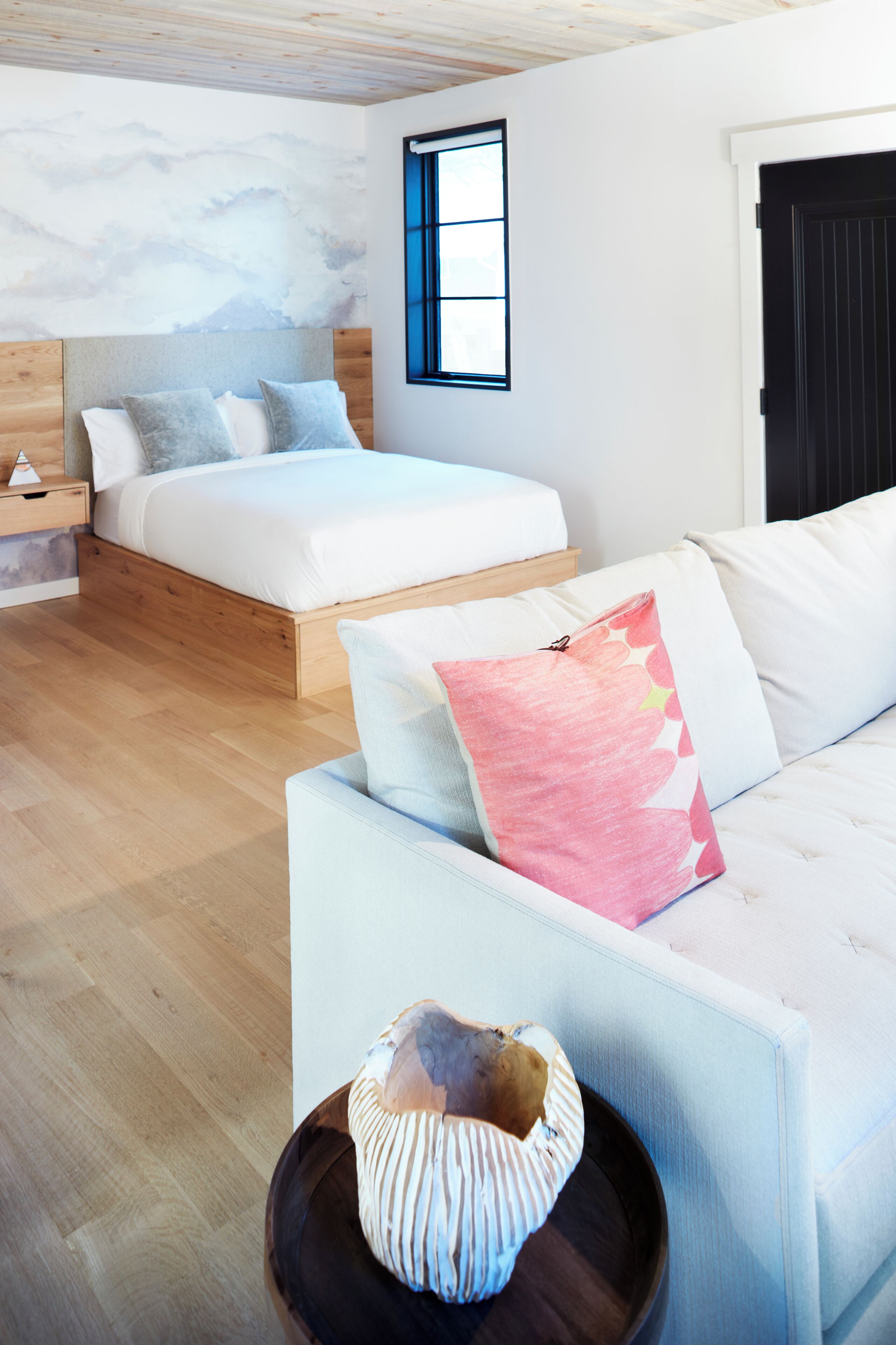 Ein modernes Schlafzimmer mit einem Bett, einer Couch und einem dekorativen Gegenstand auf einer Ablagefläche.