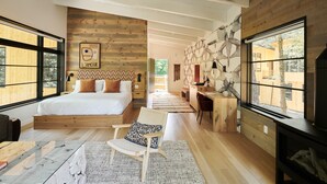 A modern bedroom with a wooden bed, a desk, and large windows.