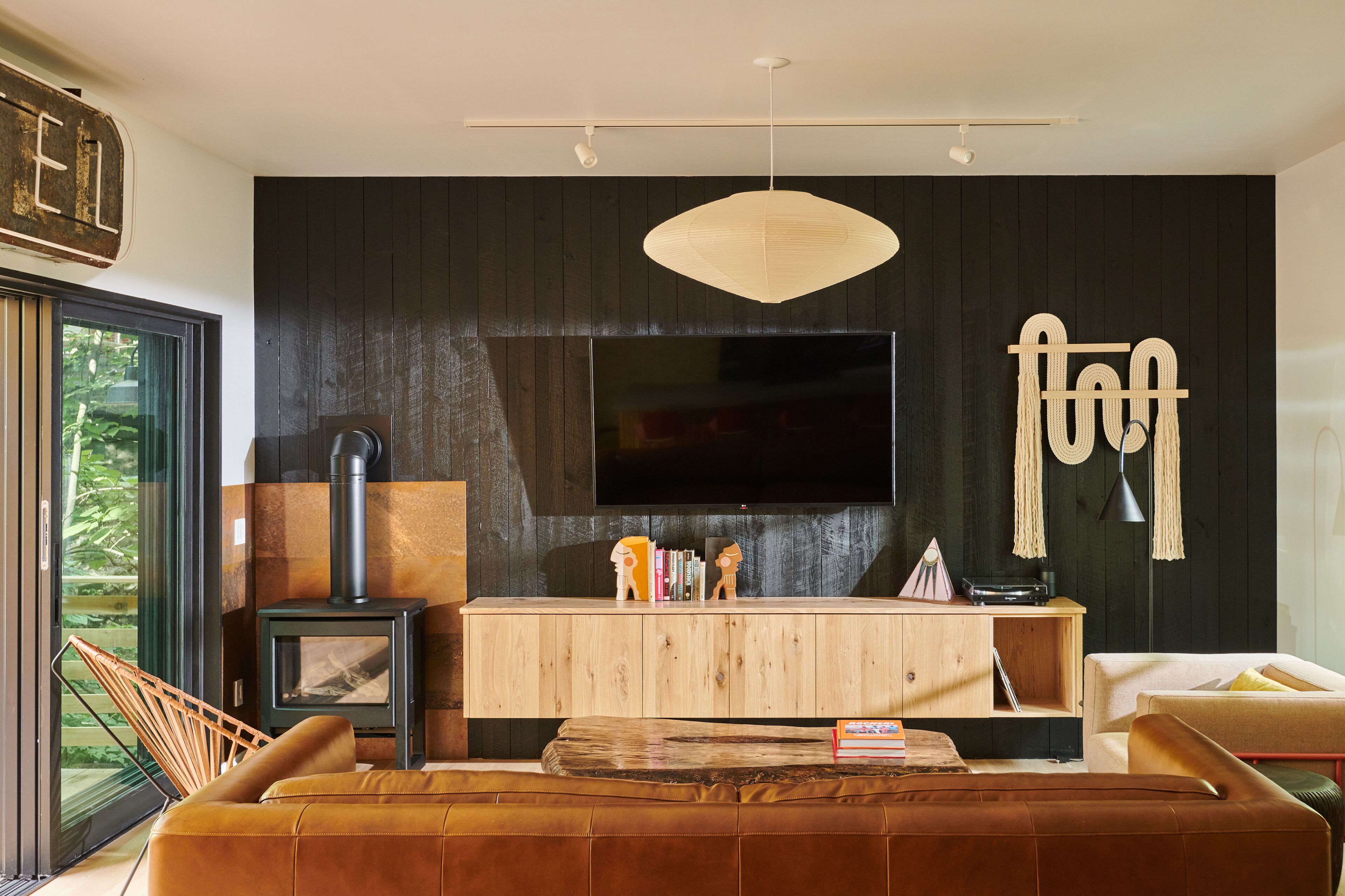 A modern living room with a large flat-screen TV, a wooden cabinet, and a sofa.