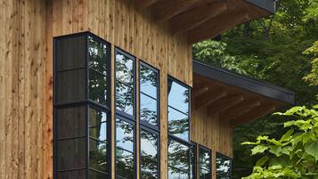 Ein modernes Holzgebäude mit großen Fenstern und einem flachen Dach.