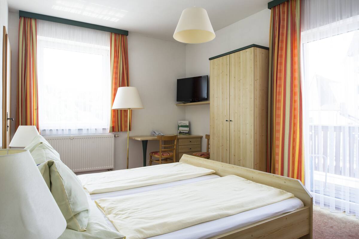 Una habitación de hotel con dos camas, un escritorio, televisor y armario.
