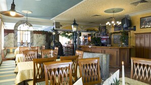 A restaurant with wooden tables and chairs, a bar area, and a ceiling with decorative lighting. - Der Dorfwirt (Rechberg)