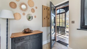 A modern interior with a dark wooden cabinet, a mirror, and woven wall decorations.
