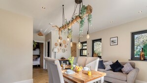 A dining area with a wooden table, chairs, and a hanging light fixture.