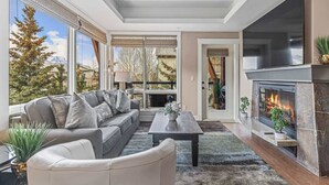 A modern living room with a fireplace, large windows, and a cozy seating area.