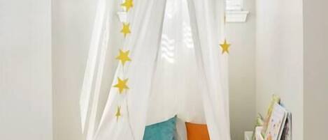 Un dormitorio acogedor con cama a dosel, adornos con motivos de estrellas y un peluche en el suelo.
