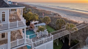 A two-story house with a pool, deck chairs, and a view of the beach. - Grey Goose: Oceanfront Escape, Backyard Oasis + Prime Location (Murrells Inlet)