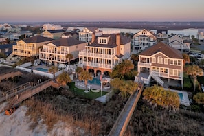 A coastal residential area with multiple houses featuring large balconies, a swimming pool, and a beach access walkway.