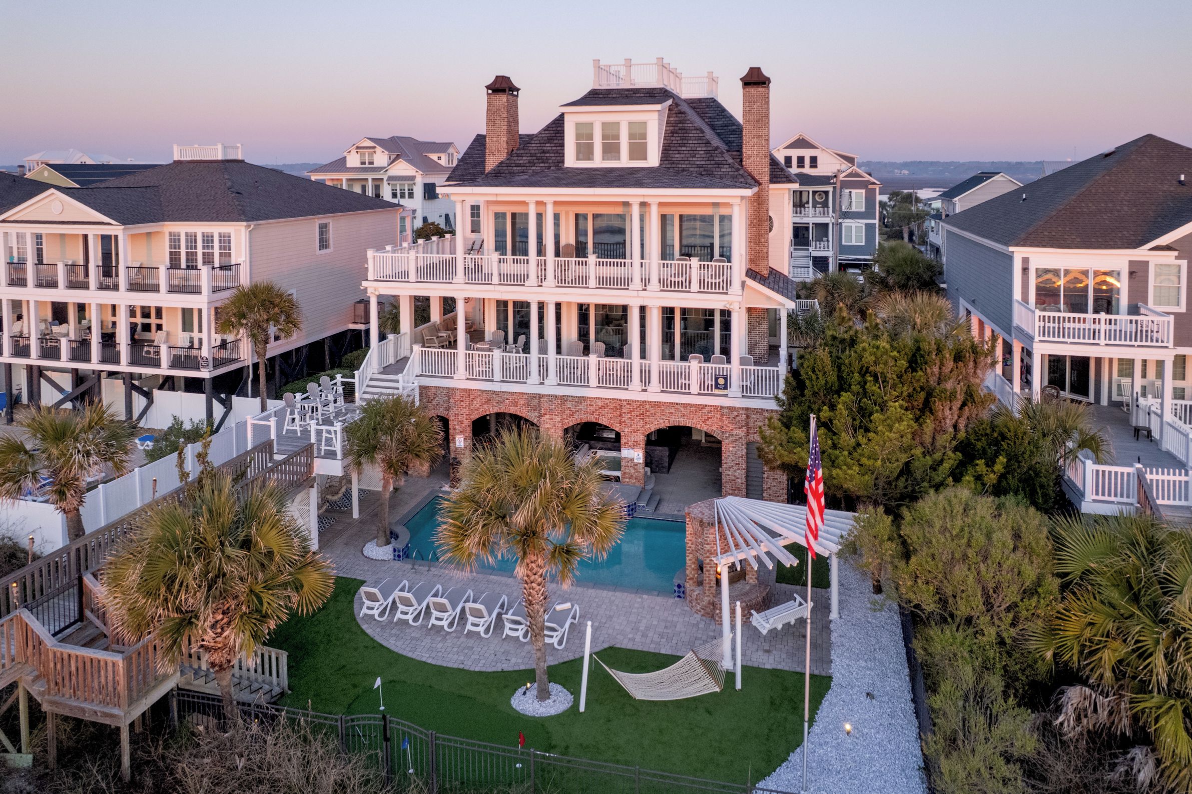 A large house with a pool, multiple balconies, and a flag.