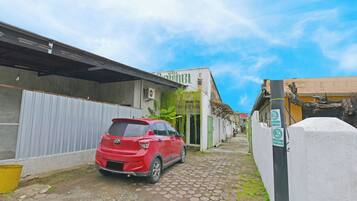 Una estrecha calle adoquinada con un coche rojo estacionado al lado. Se ve un edificio con un letrero que dice "HOTEL".