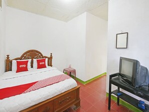 Una habitación de hotel con una cama de madera, un televisor sobre un soporte negro y una mesita con una botella de agua.