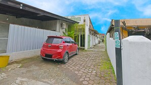 Una estrecha calle adoquinada con un coche rojo estacionado al lado. Se ve un edificio con un letrero que dice "HOTEL".