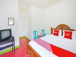 Habitación de hotel con cama, televisor, dos sillas y una mesita con botellas de agua.