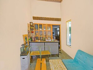 Un espacio de sala cómodo con una barra de café de madera, dos sillones, un sofá azul y un pequeño acuario.