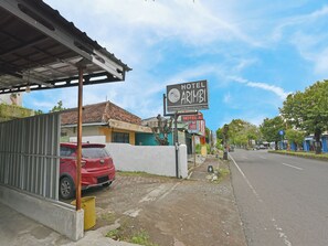 A street view with a hotel named 'Hotel Arimbi' and a red car parked on the side. - Spot ON 91270 Hotel Arimbi (Cilacap)
