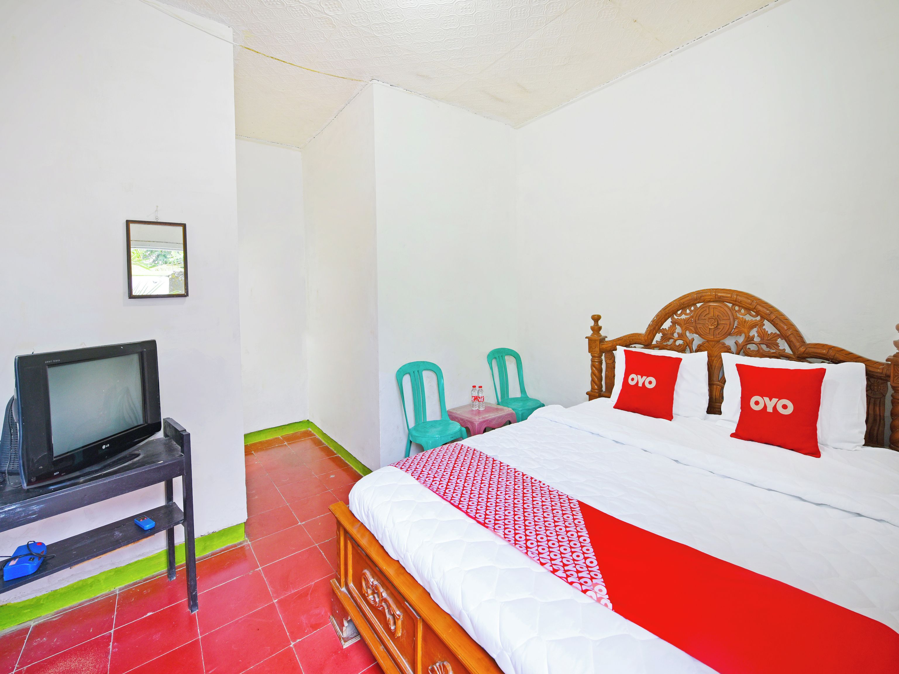 Habitación de hotel con una cama, un televisor en un mueble bajo y dos sillas.