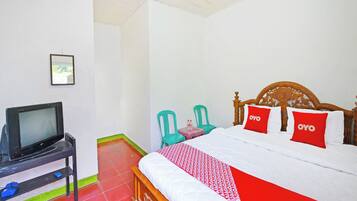 Habitación de hotel con una cama, un televisor en un mueble bajo y dos sillas.