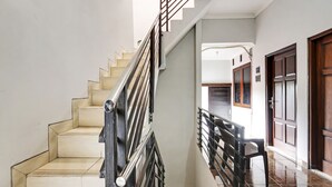 A staircase with a metal railing, beige steps, and a wooden door at the bottom.