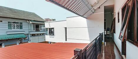 A balcony with a red roof, a white wall, and a window.