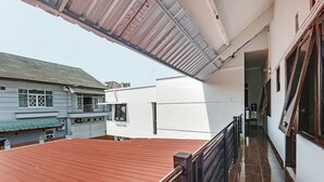 A residential building with a red roof, white walls, and a balcony with a metal railing.
