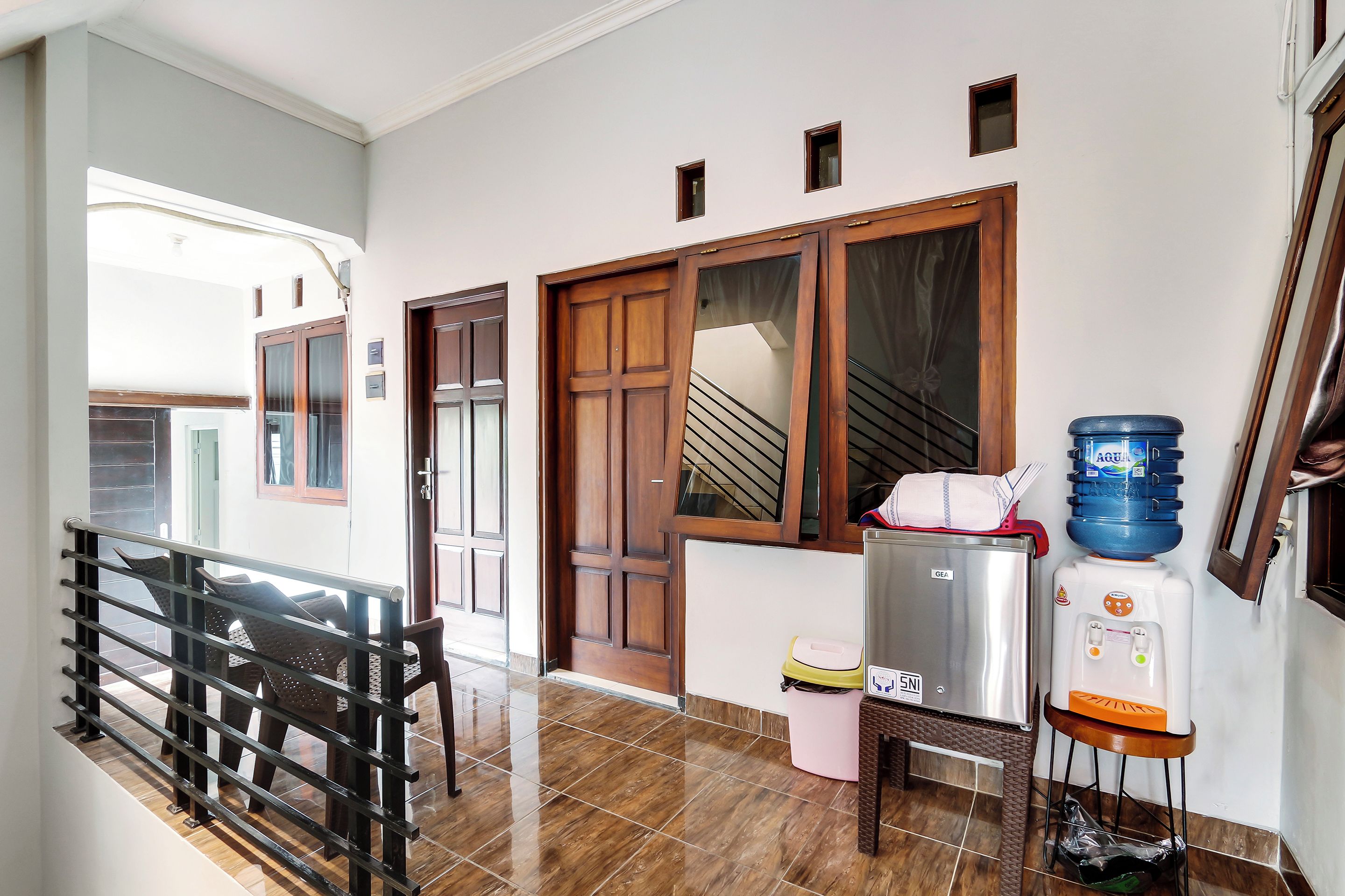 A hallway with a staircase, a water dispenser, and a trash bin.