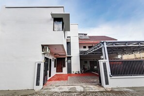 Un bâtiment moderne doté d’une entrée sécurisée par un portail, d’un toit recouvert de tuiles rouges et d’une zone abritée surmontée d’un toit en métal.